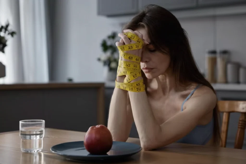 mulher com anorexia com as mão amarradas por uma fita métrica