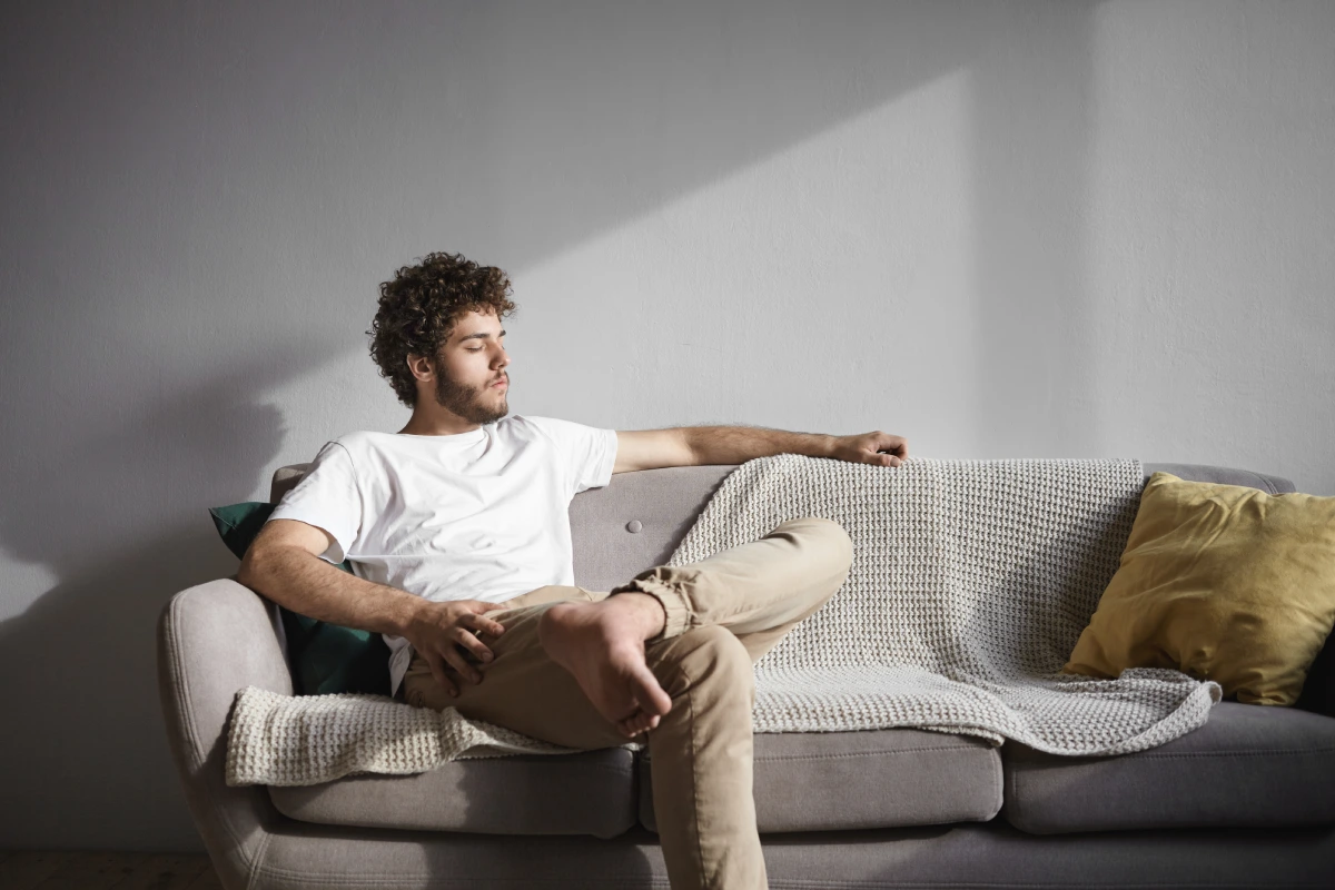homem sentado no sofá pensando no que fazer