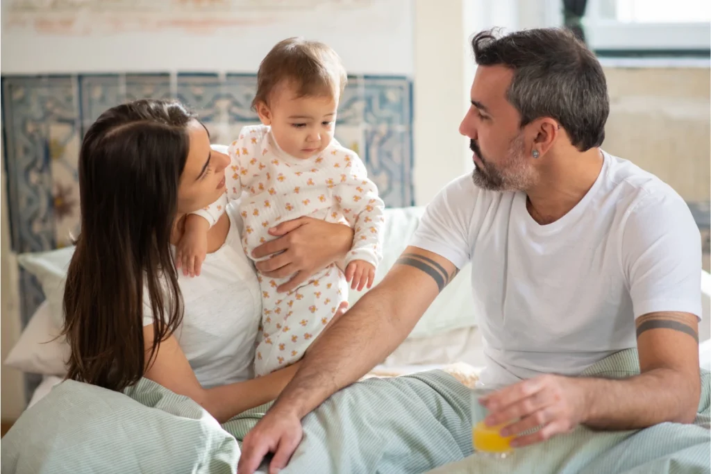 casal com bebê sentados juntos na cama