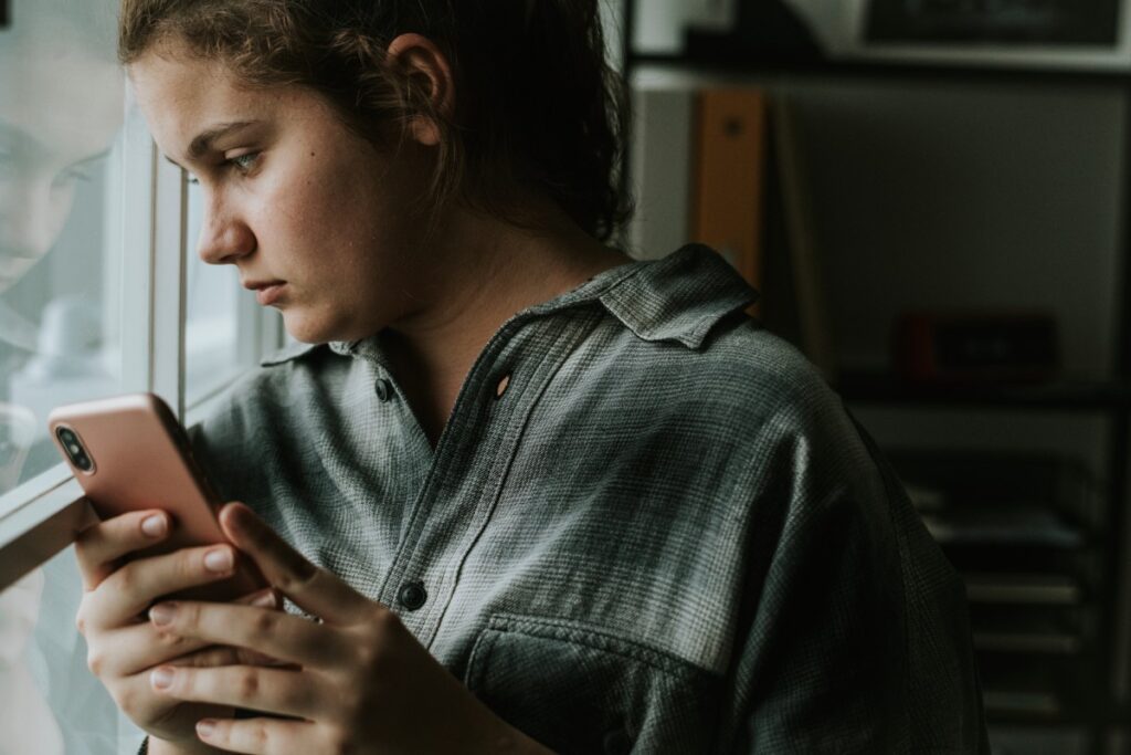 adolescente triste olhando para o celular